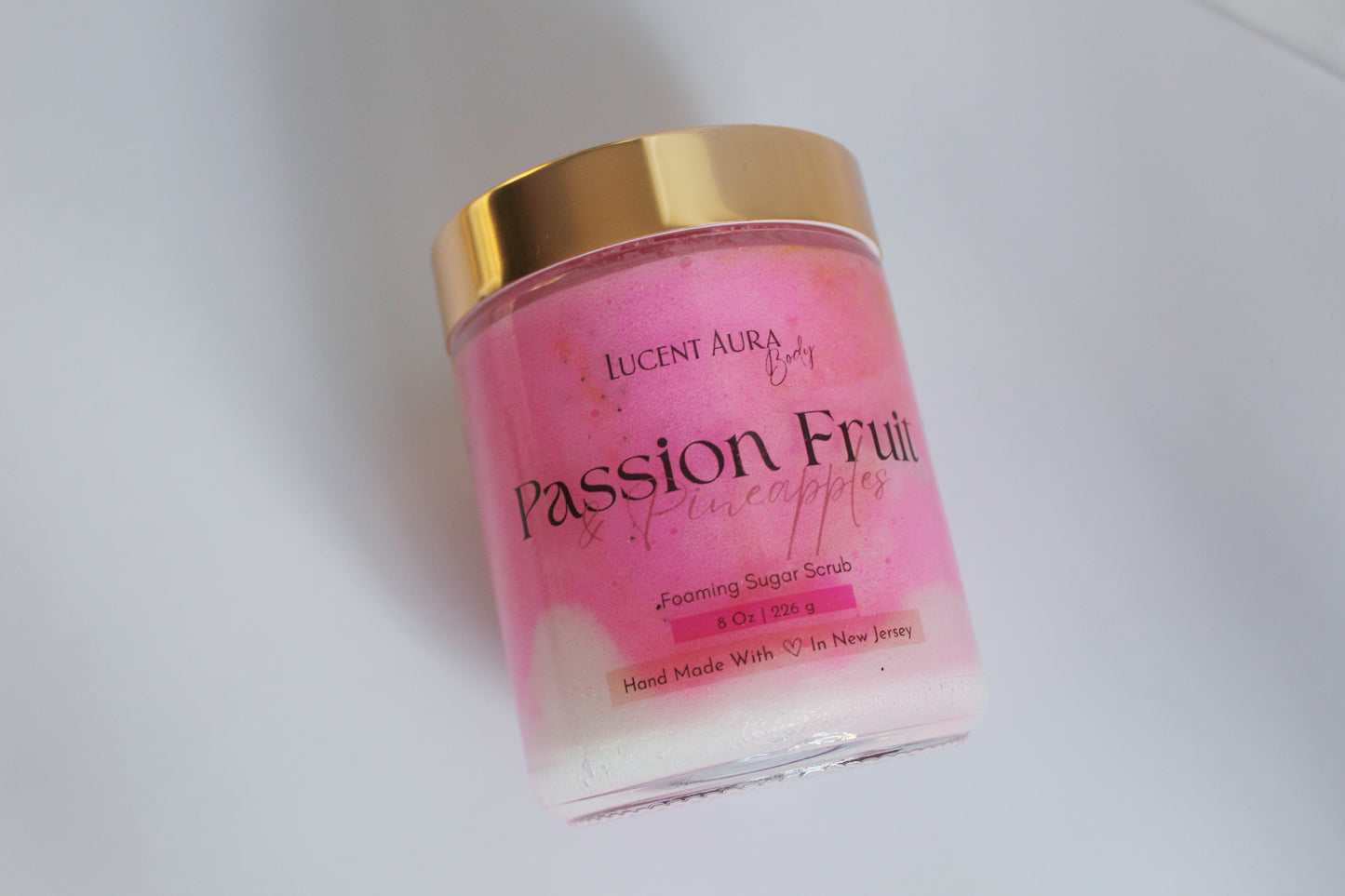 Pink jar of sugar scrub with gold lid on a white background
