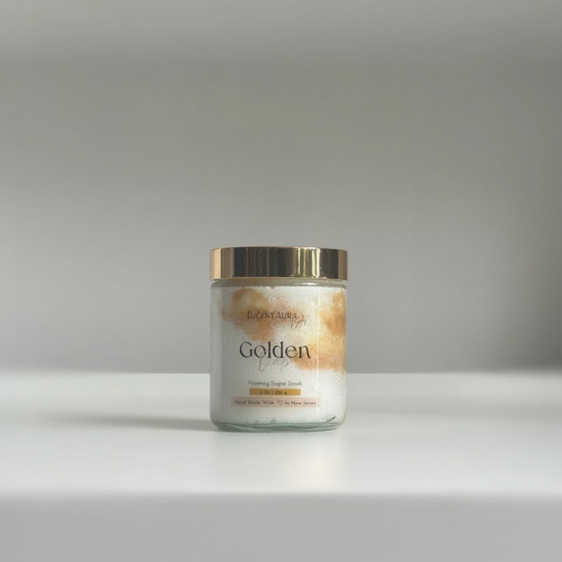 Jar of Golden Oats Sugar Scrub with a gold lid on a gray background