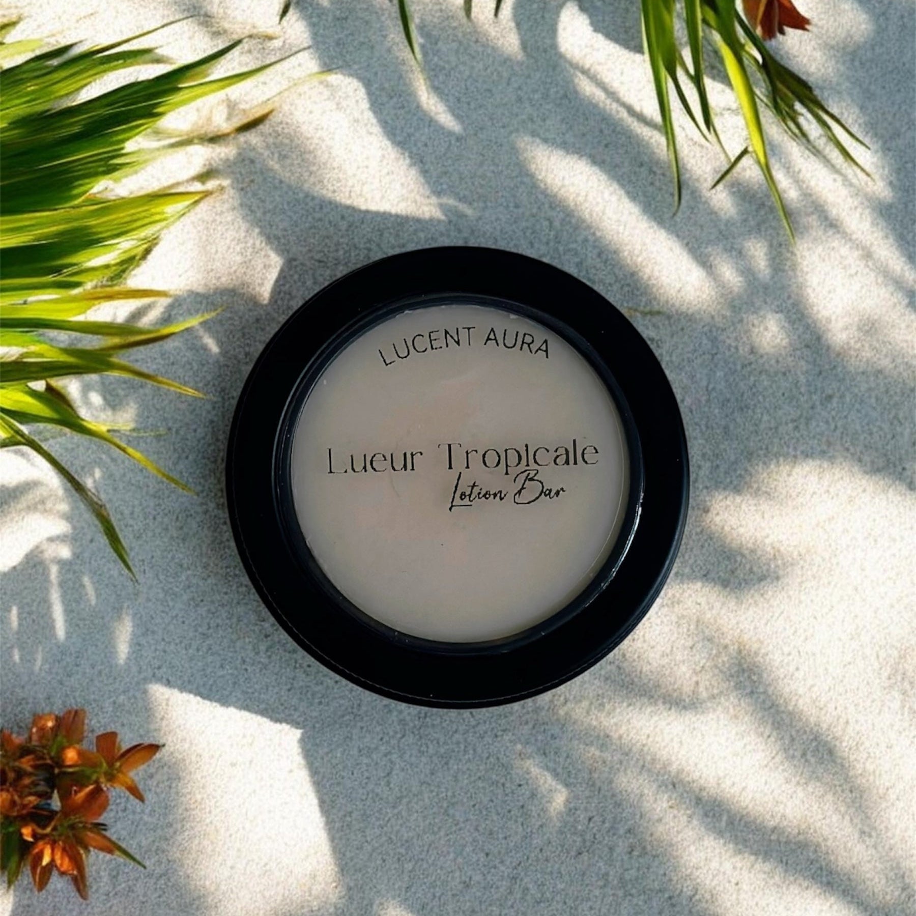 Lucent Aura Lueur Tropicale Lotion Bar on sand with green leaves