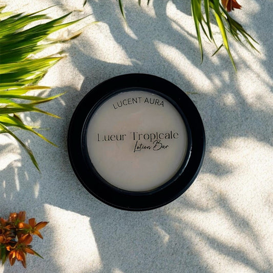 Lucent Aura Lueur Tropicale Lotion Bar on sand with green leaves