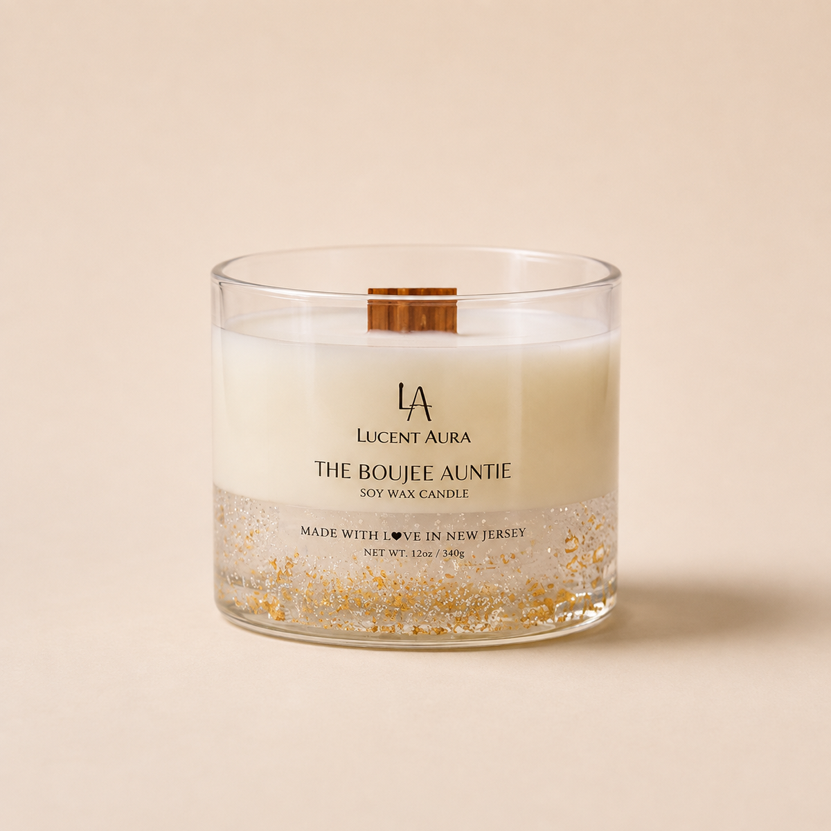 A Lucent Aura soy wax candle in a clear glass jar with a wooden wick, featuring a white wax body, a gold glitter bottom layer, and a small wooden slice insert on the lid, set against a solid beige background.