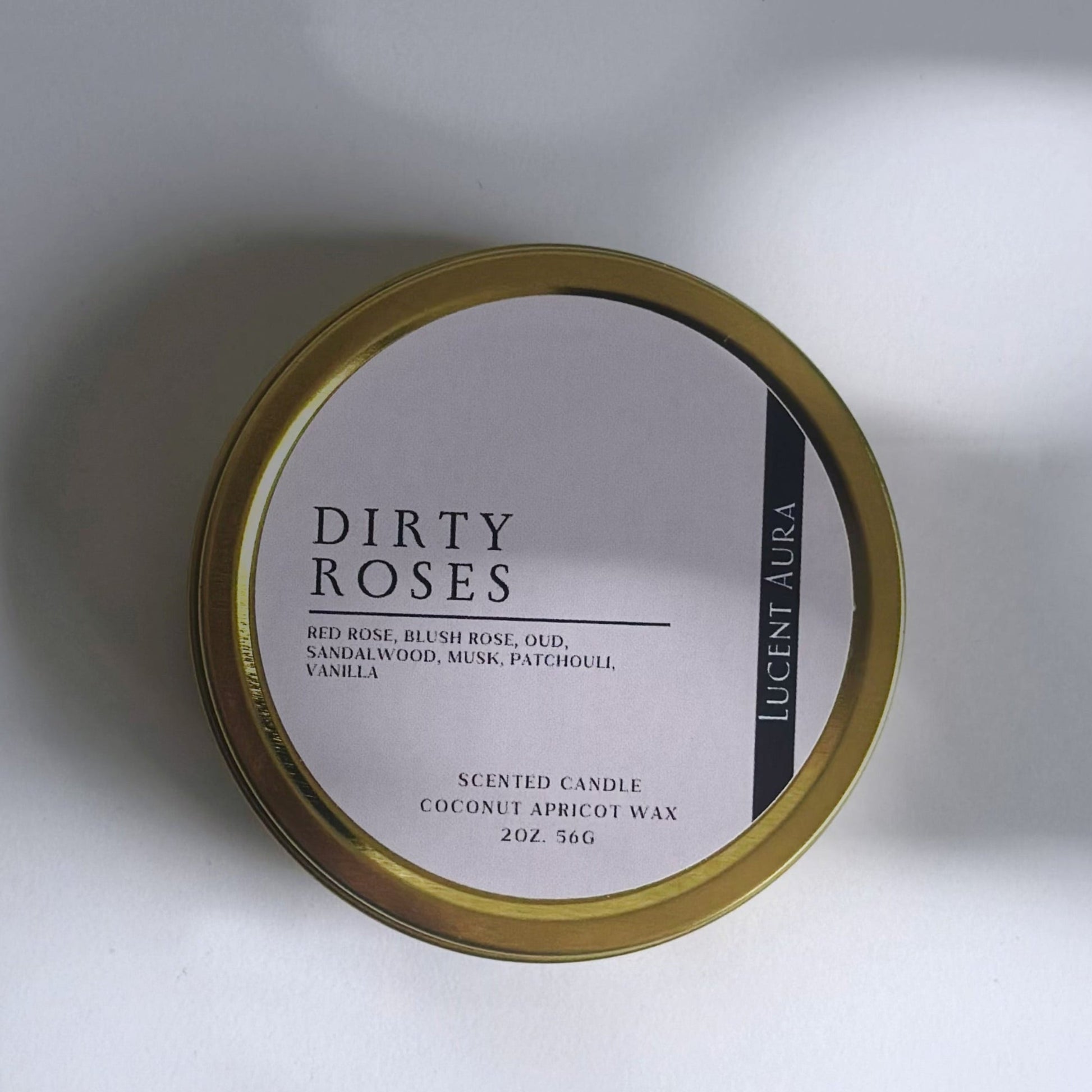 Candle tin labeled 'Dirty Roses' on a white background in a gold tin with soft shadows.