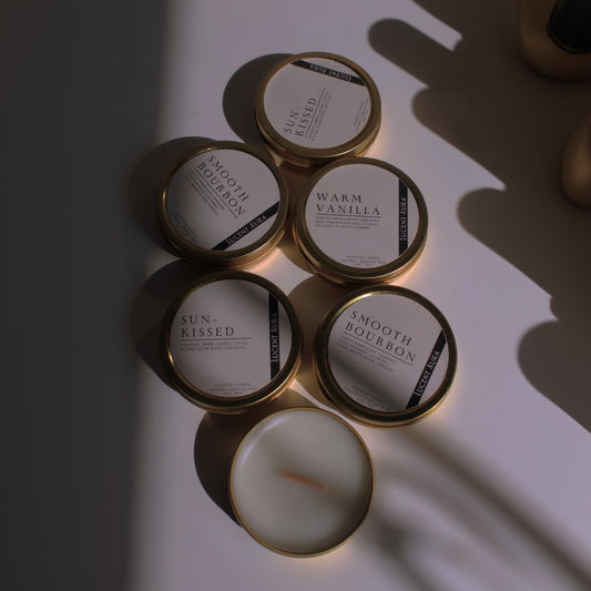 Collection of candles with labeled containers on a reflective surface