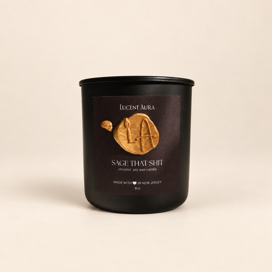 A matte black soy wax candle jar by Lucent Aura with a dark brown label featuring a gold wax seal logo and the scent name 'Sage That Shit'.