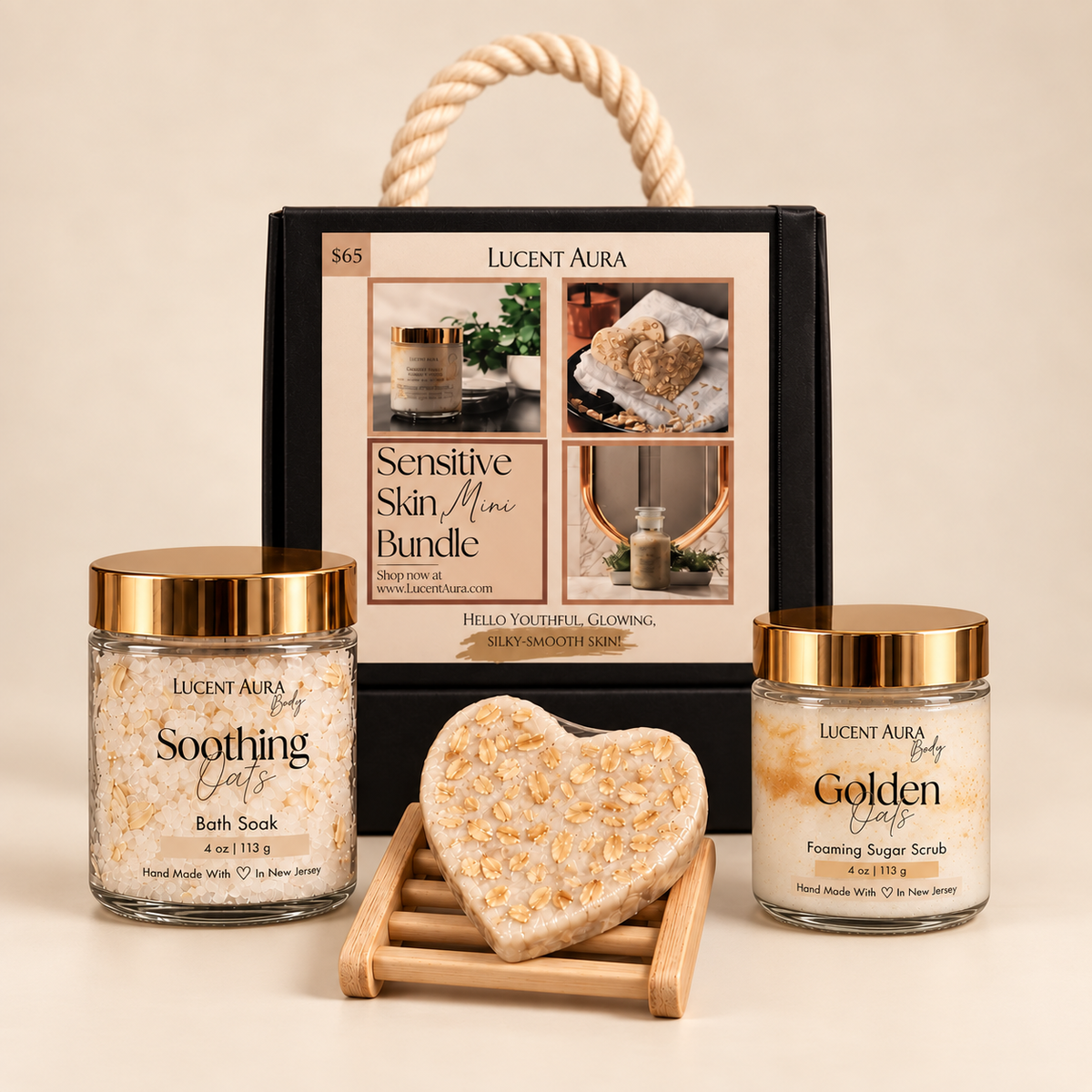 Lucent Aura Sensitive Skin Mini Bundle gift set featuring a black presentation box with a rope handle, a jar of Soothing Oats Bath Soak, a jar of Golden Glow Foaming Sugar Scrub, and a heart-shaped oat scrub bar on a wooden stand, set against a warm beige background.