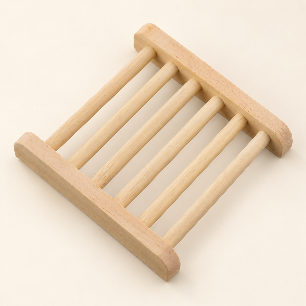 A light natural wood soap holder with rounded corners and six parallel support bars, shown on a solid cream background.