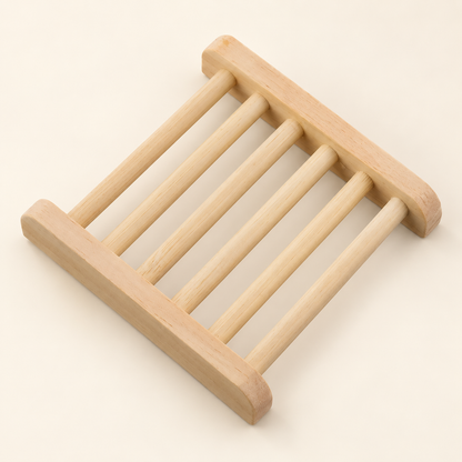 A light natural wood soap holder with rounded corners and six parallel support bars, shown on a solid cream background.