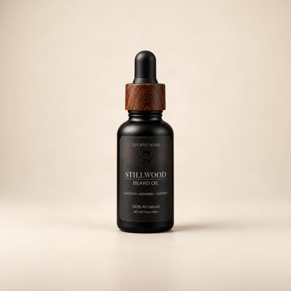 A bottle of Lucent Aura Stillwood Beard Oil with a black dropper cap, a dark wood collar, and a black label, set against a solid beige background.