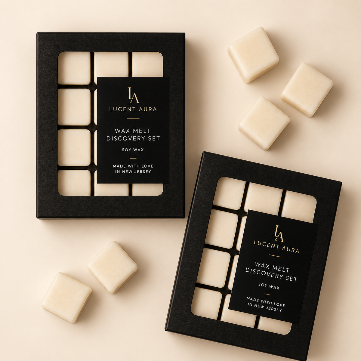 Two black Lucent Aura Wax Melt Discovery Set boxes arranged on a warm beige background, with several cream-colored wax melts scattered around them.