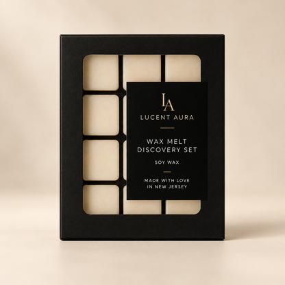 A black rectangular box for a Lucent Aura Wax Melt Discovery Set, showing six cream-colored wax melts through cutout sections on a warm beige background.