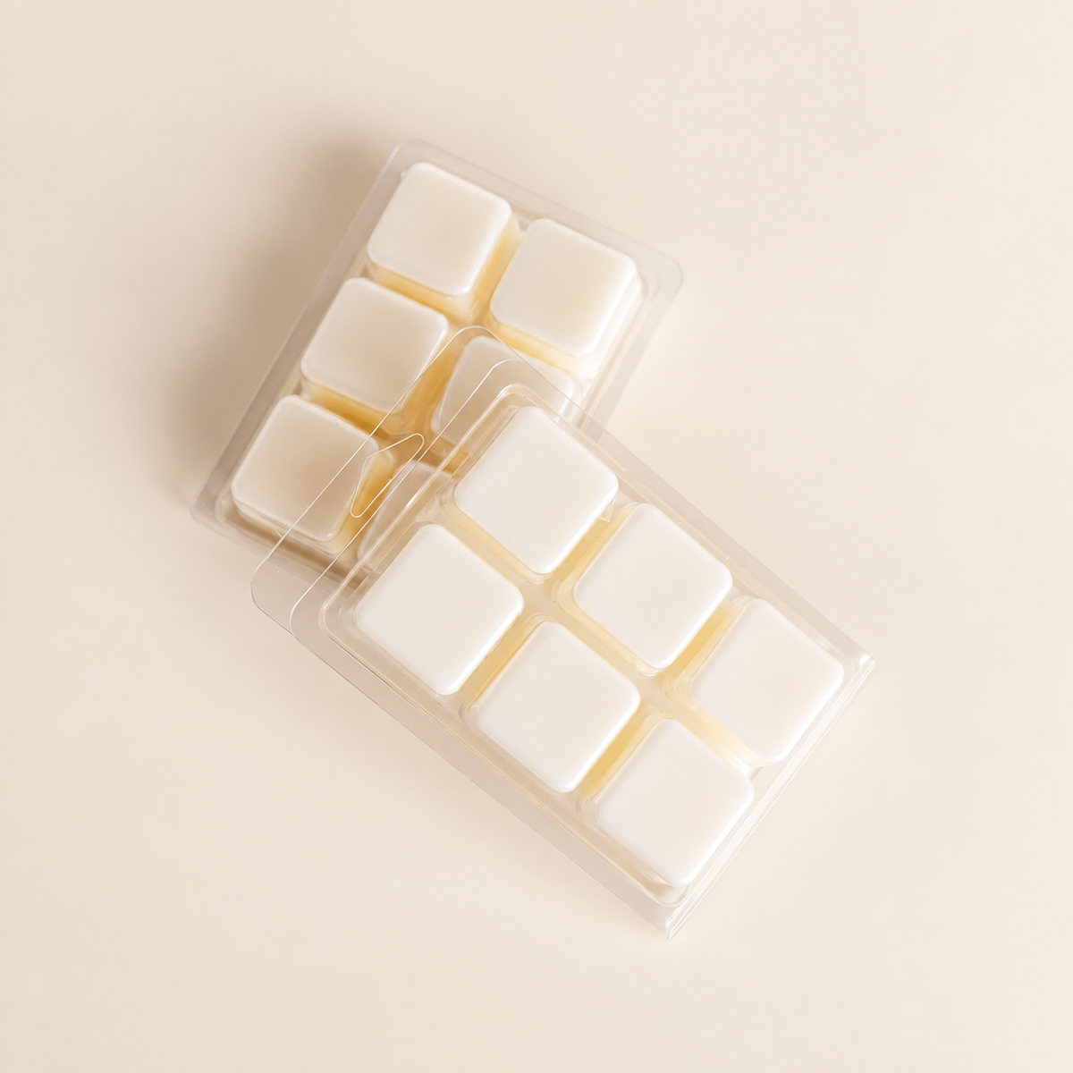 Two clear plastic Wax Melts packs containing white square wax melts, arranged diagonally on a solid beige background.