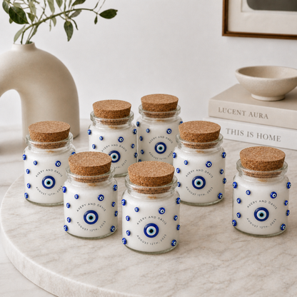 Set of small glass jars with cork lids on a marble surface, featuring blue evil eye designs.